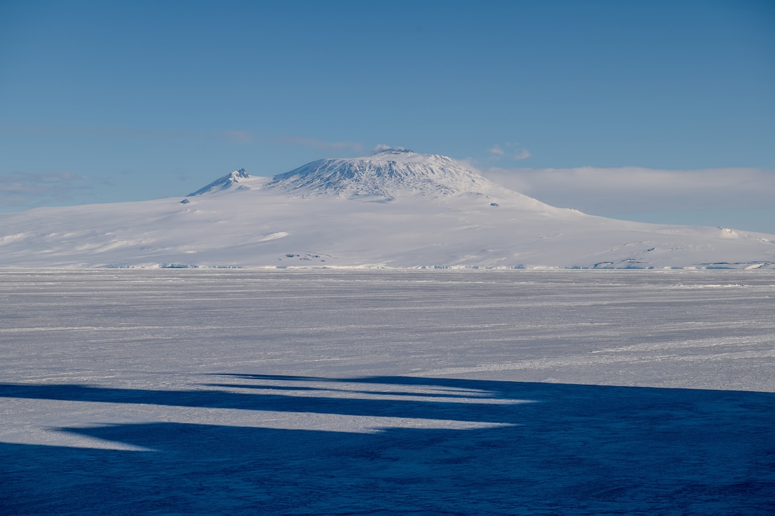 A snow-covered mountain visible with ice in the foreground;