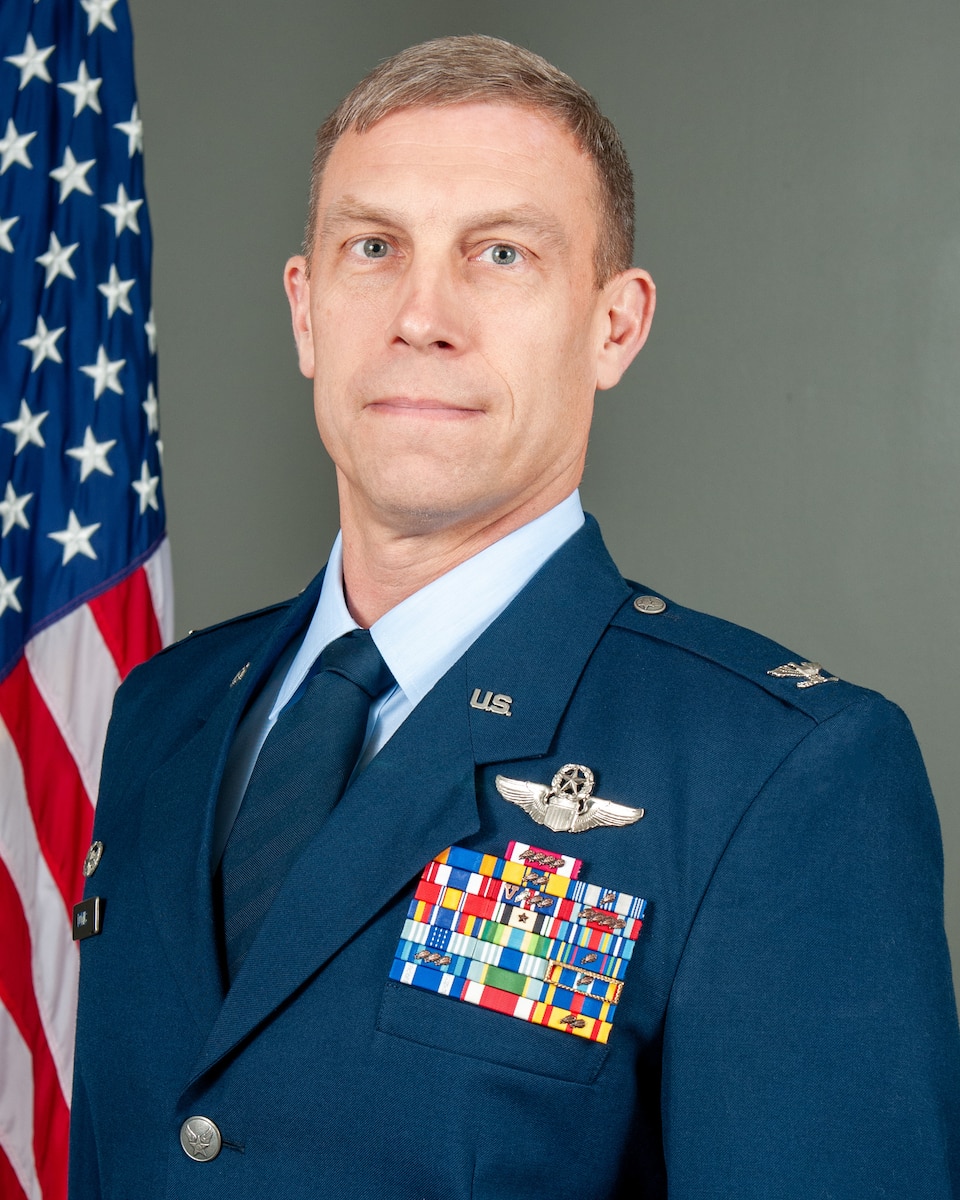U.S. Air Force Col. George H.H. Downs, commander of the 125th Fighter Wing, in the Air Force Dress uniform, with the American flag behind him.