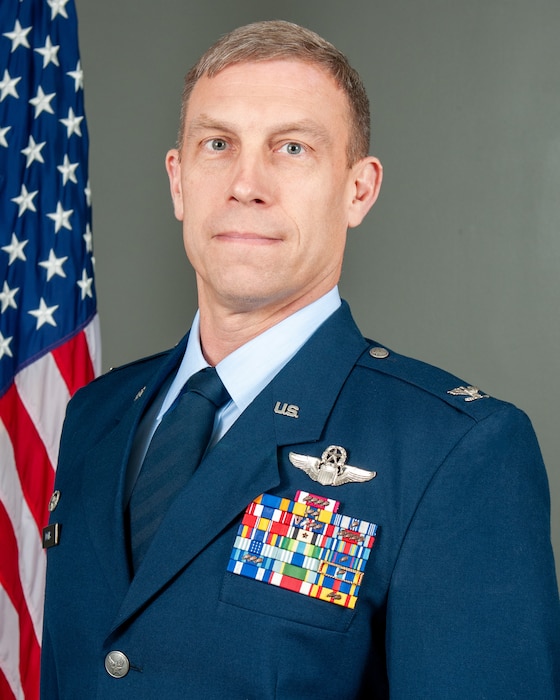 U.S. Air Force Col. George H.H. Downs, commander of the 125th Fighter Wing, in the Air Force Dress uniform, with the American flag behind him.
