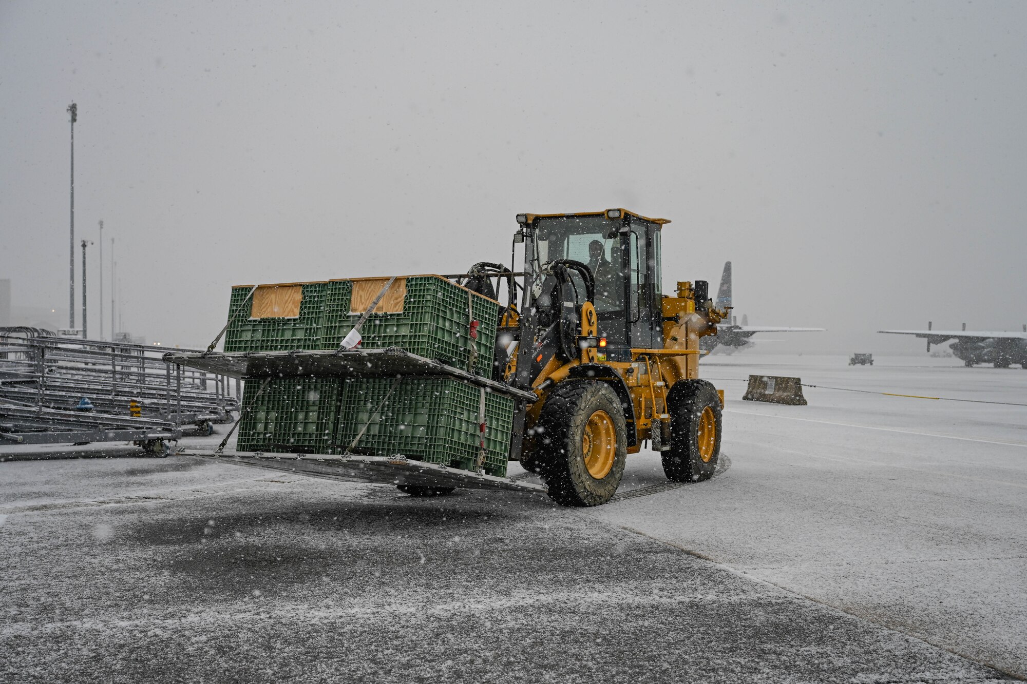 A forklift carries cargo under snowfall.
