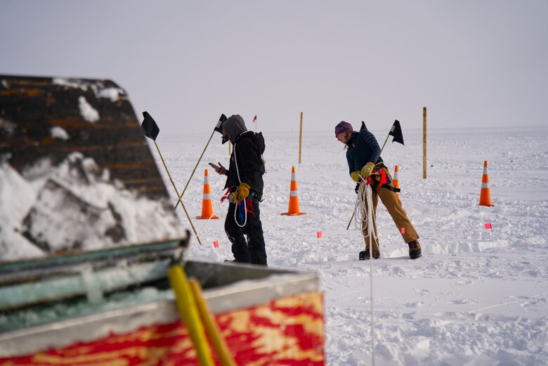 Cold Regions Research and Engineering Laboratory (CRREL) scientist Hannah Wittmann (right) peers into a crevasse along the roughly 1,000-mile long South Pole Traverse (SPoT) route. Wittmann and fellow scientist Dr. Zoe Courville recently returned from Antarctica, where they performed critical crevasse detection and mitigation on the most problematic portion of the flagged trail, a three-mile wide shear zone where the McMurdo and Ross ice shelves meet.
