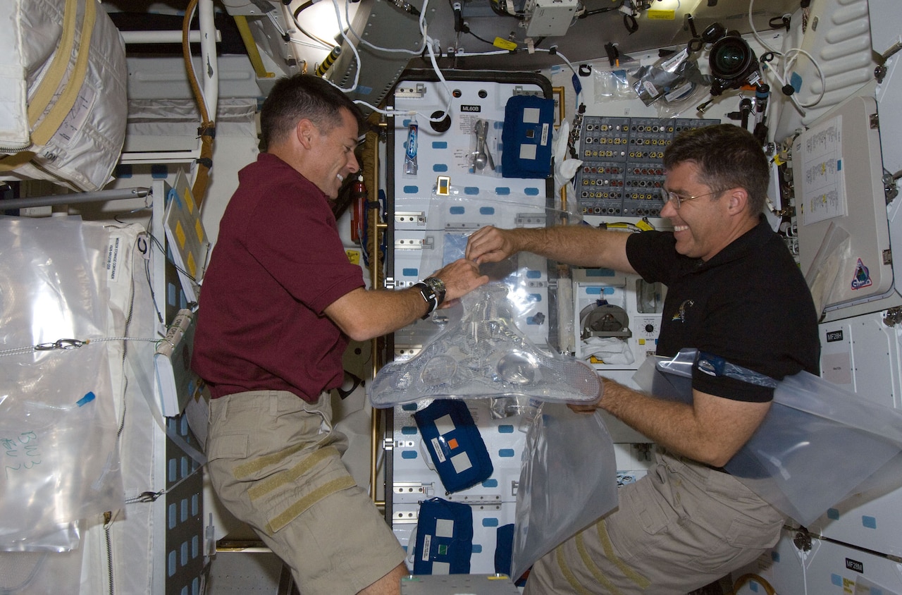 Two people float in a space shuttle.