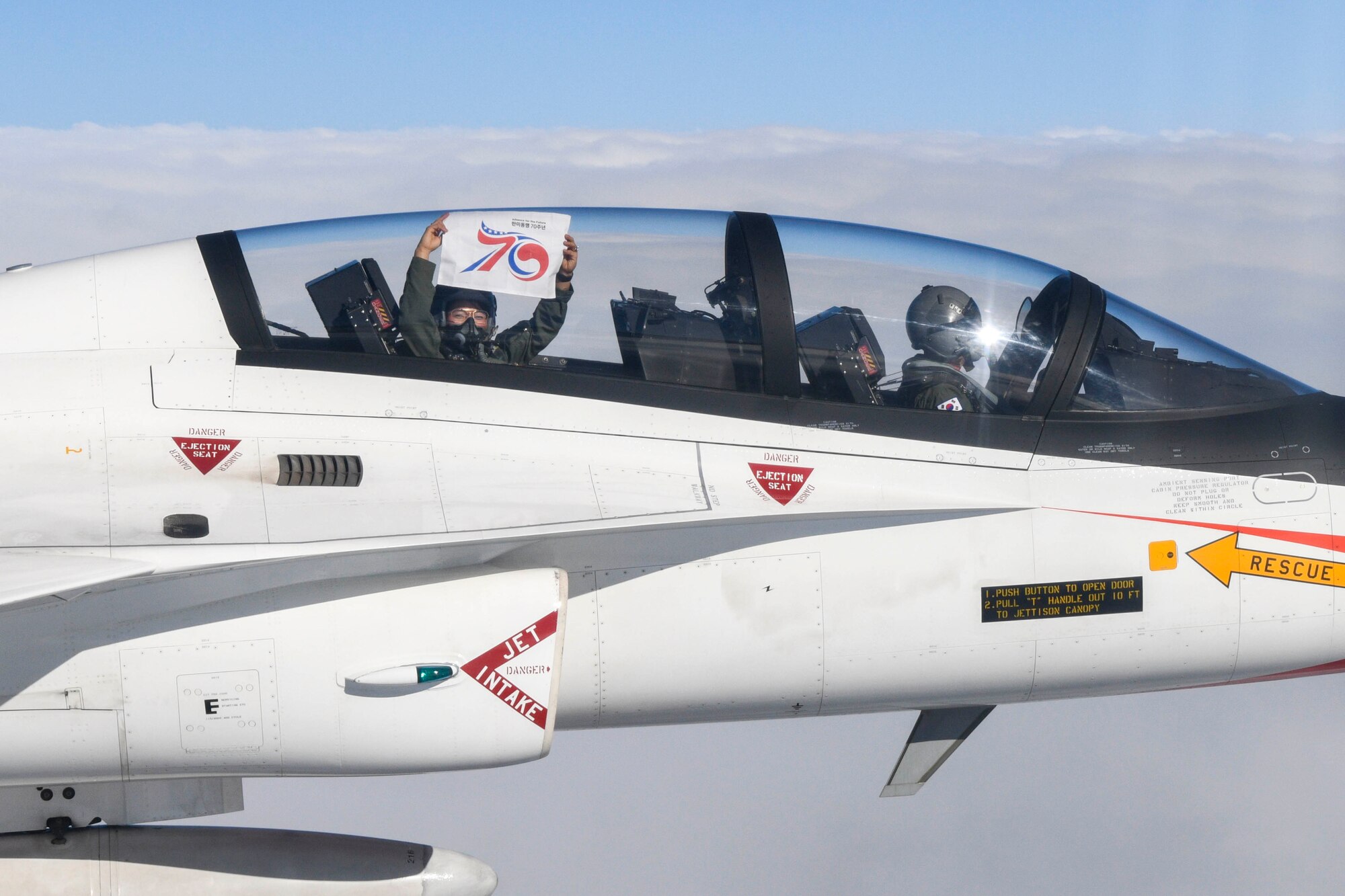 U.S. Air Force 1st Lt. Michelle Chang, 51st Fighter Wing public affairs officer, holds up a ROK-U.S. Alliance 70th anniversary flag as Republic of Korea Air Force Maj. Cho Wonbin, KT-50 instructor pilot, flies over the ROK during an incentive flight near Seoul, October 21, 2023.