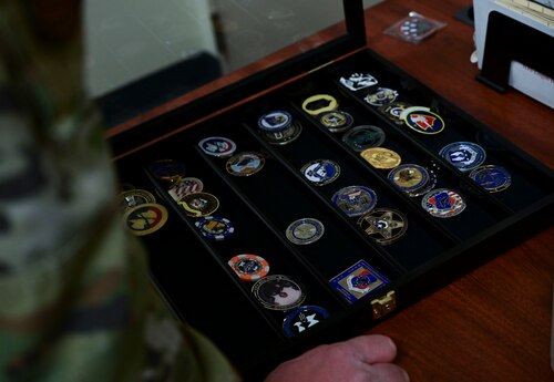 U.S. Air Force Master Sgt. Eric Emerson, 17th Security Forces Squadron standardization and evaluation superintendent, displays some of the coins he has collected throughout his career, Goodfellow Air Force Base, Texas, Dec. 5, 2023. Emerson has deployed to three locations while stationed at F.E. Warren AFB and Lackland AFB. (U.S. Air Force photo by Airman 1st Class Madison Collier)