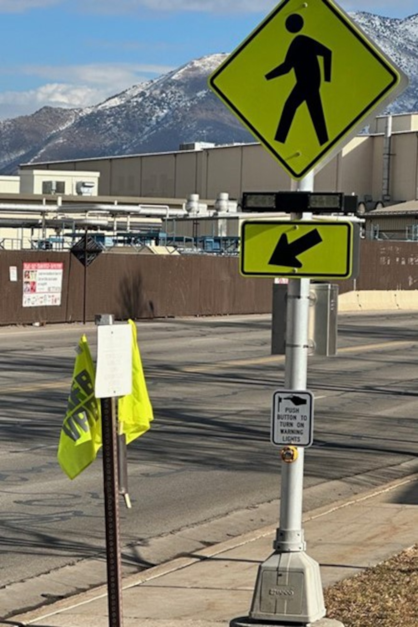A crosswalk sign with industrial buildings around