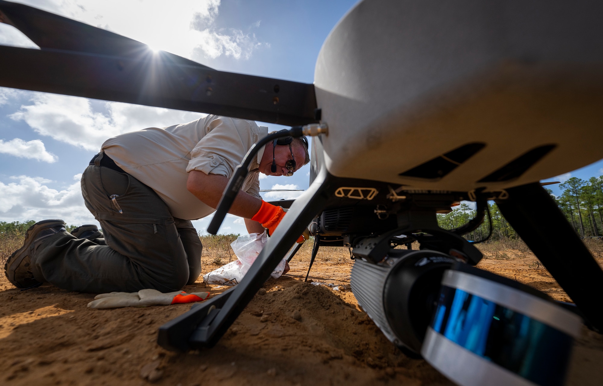 A man kneels next to an unmanned drone.