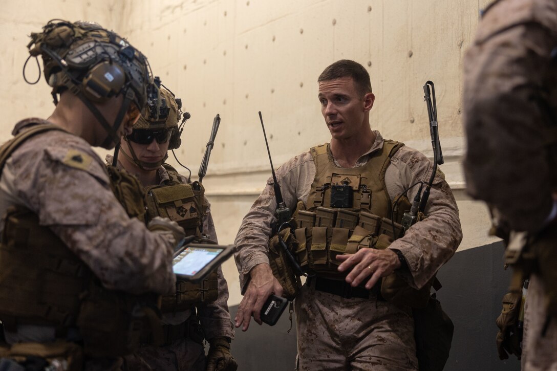 U.S. Marine Corps Maj. Travis Bird (right), the company commander with Alpha Company, Battalion Landing Team 1/6, 26th Marine Expeditionary Unit (Special Operations Capable) (MEU(SOC)), speaks with Marines prior to conducting a tactical recovery of aircraft and personnel exercise aboard amphibious assault ship USS Bataan (LHD 5), Dec. 21, 2023. Marines and Sailors of the 26th Marine Expeditionary Unit (Special Operations Capable), embarked on the ships of the Bataan Amphibious Ready Group, are on a scheduled deployment as the Tri-Geographic Combatant Command crisis response force with elements deployed to the U.S. 5th Fleet and U.S. 6th Fleet areas of operation to increase maritime security and stability, and to defend U.S., Allied, and Partner interests. (U.S. Marine Corps photo by Sgt. Matthew Romonoyske-Bean)