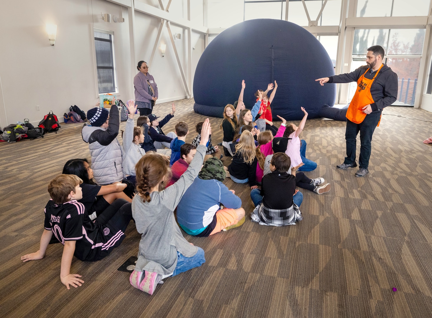 STEM coordinator, Samuel De Lano, Naval Undersea Warfare Center Division Keyport, answers questions from local fourth and fifth grade students from Silver Ridge Elementary School, before they enter a portable planetarium, during STEM Days activities Nov. 15, 2023, at the Puget Sound Navy Museum, in Bremerton Washington. (U.S Navy Photo by Wendy Hallmark)