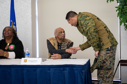 Reginald E. Petty shakes hands with an airman from behind the panel desk