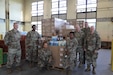 Air Force, Navy and Army personnel pose for a picture after unwrapping a couple pallets of coffee at Joint Base McGuire-Dix-Lakehurst, New Jersey.