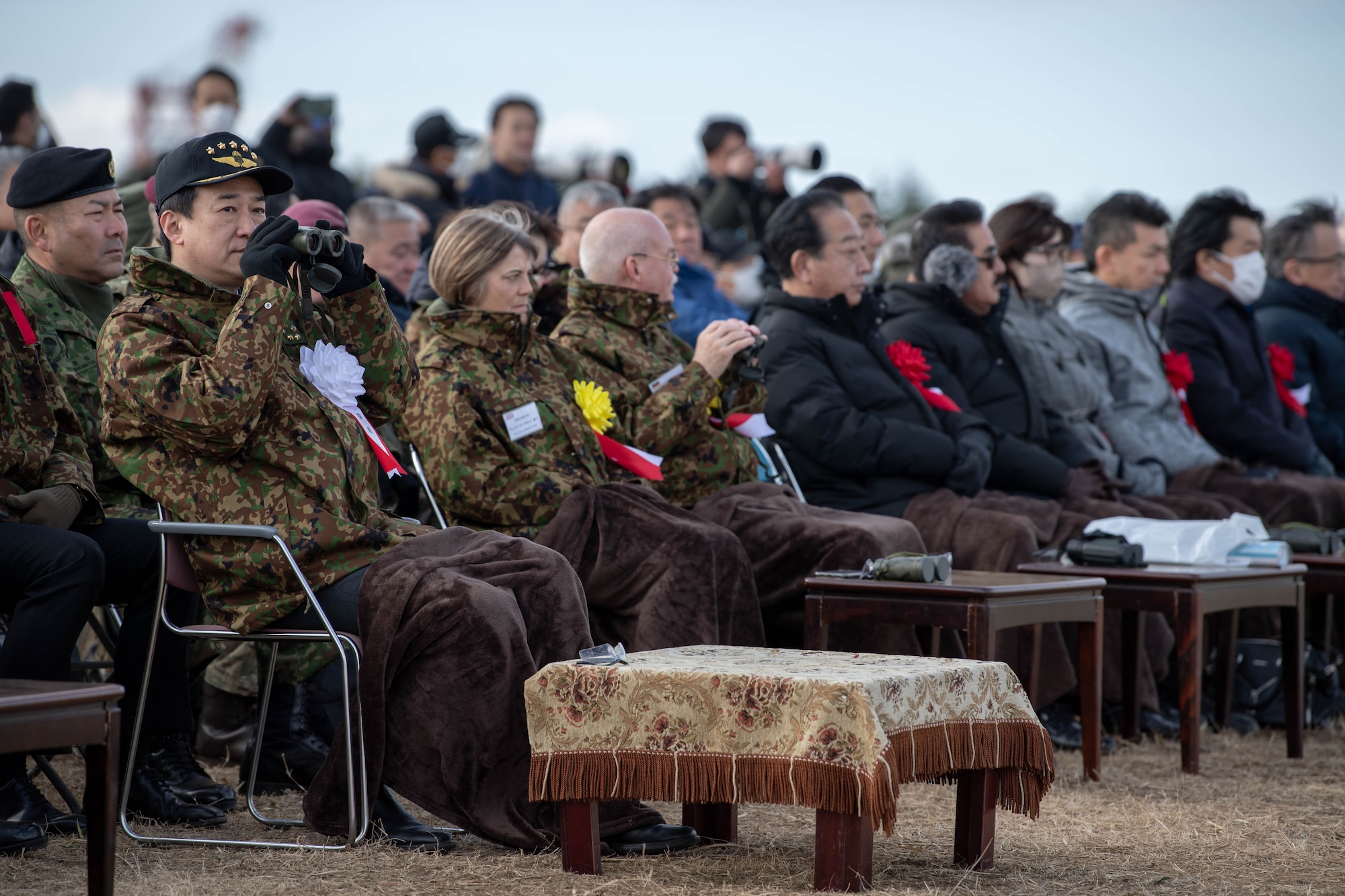 Japan Minister of Defense Minoru Kihara observes the annual New Year's Jump exhibition through a pair of binoculars at Camp Narashino, Japan.