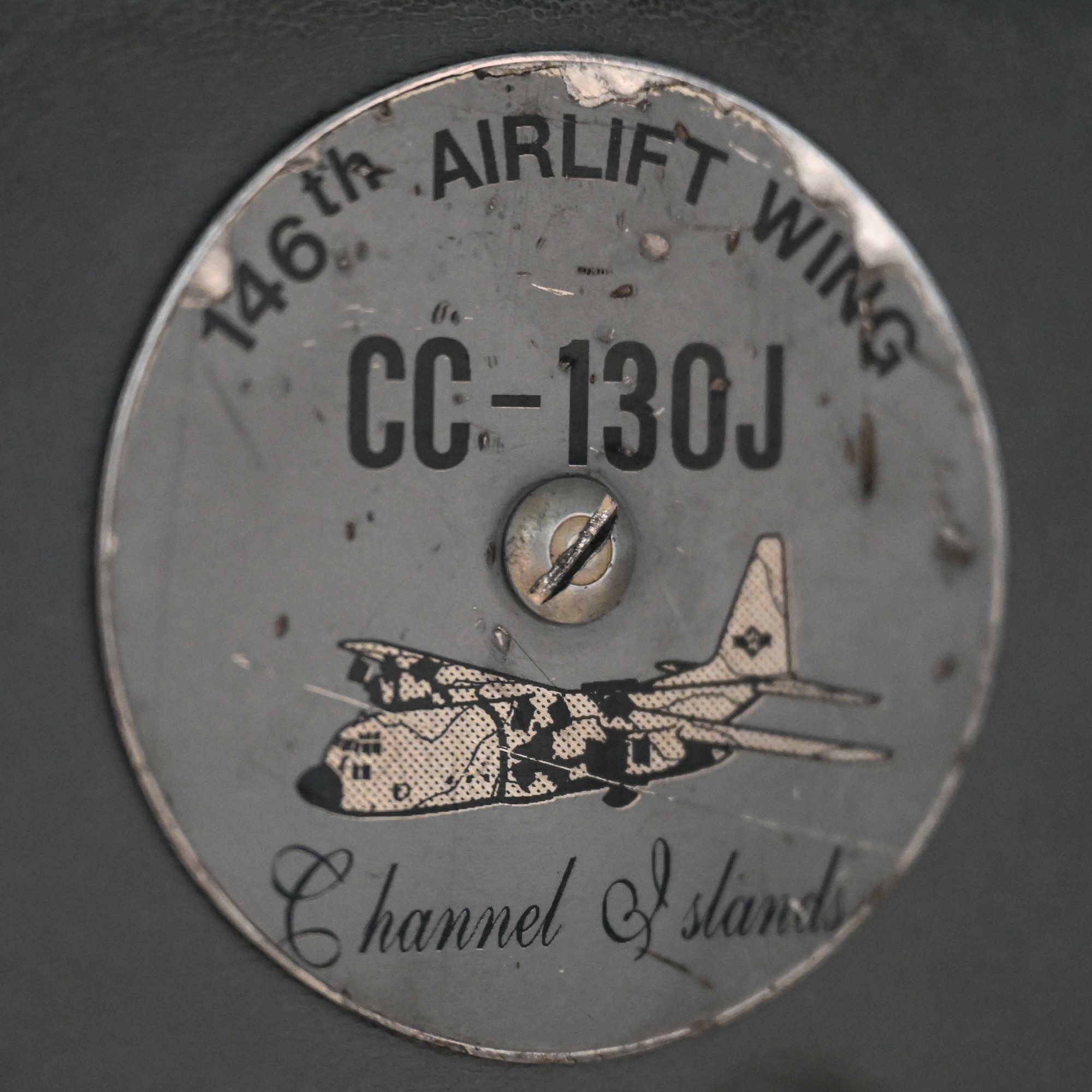 An aircraft insignia bolted to a seat, tattered.
