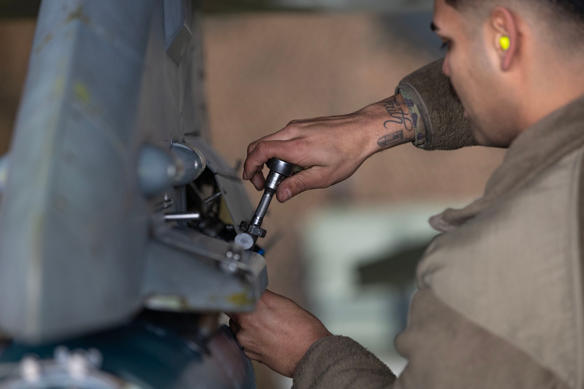 U.S. Air Force Staff Sgt. Jorge Aparicio Aguilar, 36th Fighter Generation Squadron weapons load crew chief, tightens a bolt securing a weapon on a F-16 Fighting Falcon during a weapons load crew of the quarter competition at Osan Air Base, Republic of Korea, Jan. 5, 2024. During the competition, load crew members are evaluated on safety, speed, reliability, technical errors and use of the checklist. (U.S. Air Force photo by Staff Sgt. Aubree Owens)
