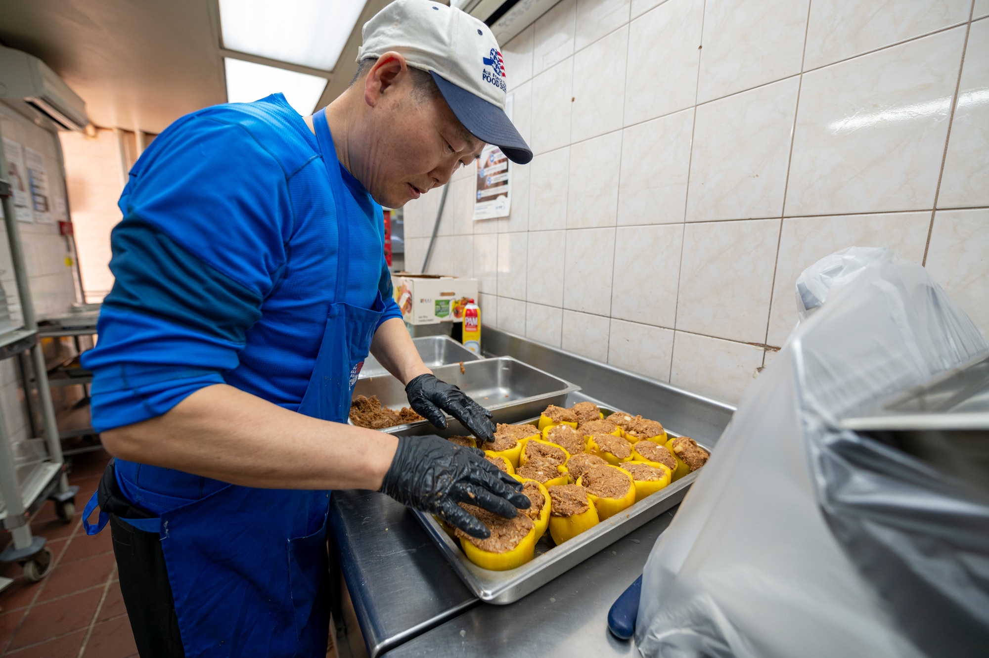 Chong Chol Yi, 51st Force Support Squadron food services specialist, prepares stuffed bell peppers at Osan Air Base, Republic of Korea, Jan. 8, 2024. Food service specialists from the 51st FSS work together to prepare, cook and serve food to Osan Airmen, keeping them nourished and ready to accomplish their daily tasks. (U.S. Air Force photo by Senior Airman Trevor Gordnier)