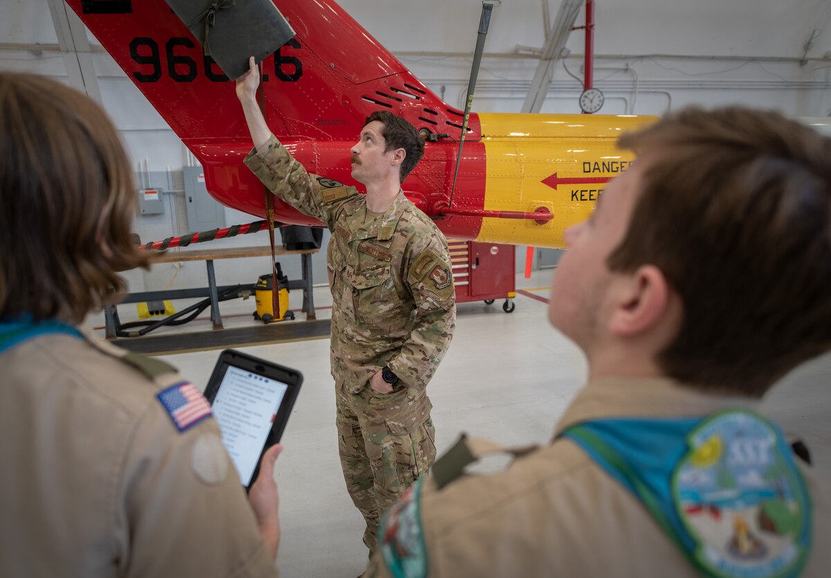 A special missions aviator, points out the tail rotor on a UH-1N Huey helicopter to a group of scouts.