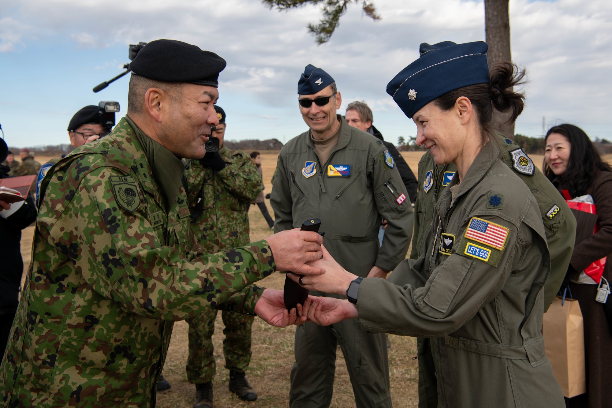 Japan Ground Self-Defense Force Maj. Gen. Junya Wakamatsu, 1st Airborne Brigade commander, accepts a gift from U.S. Air Force Lt. Col. Kira Coffey, 36th Airlift Squadron commander, following the annual New Year's Jump exhibition at Camp Narashino, Japan.
