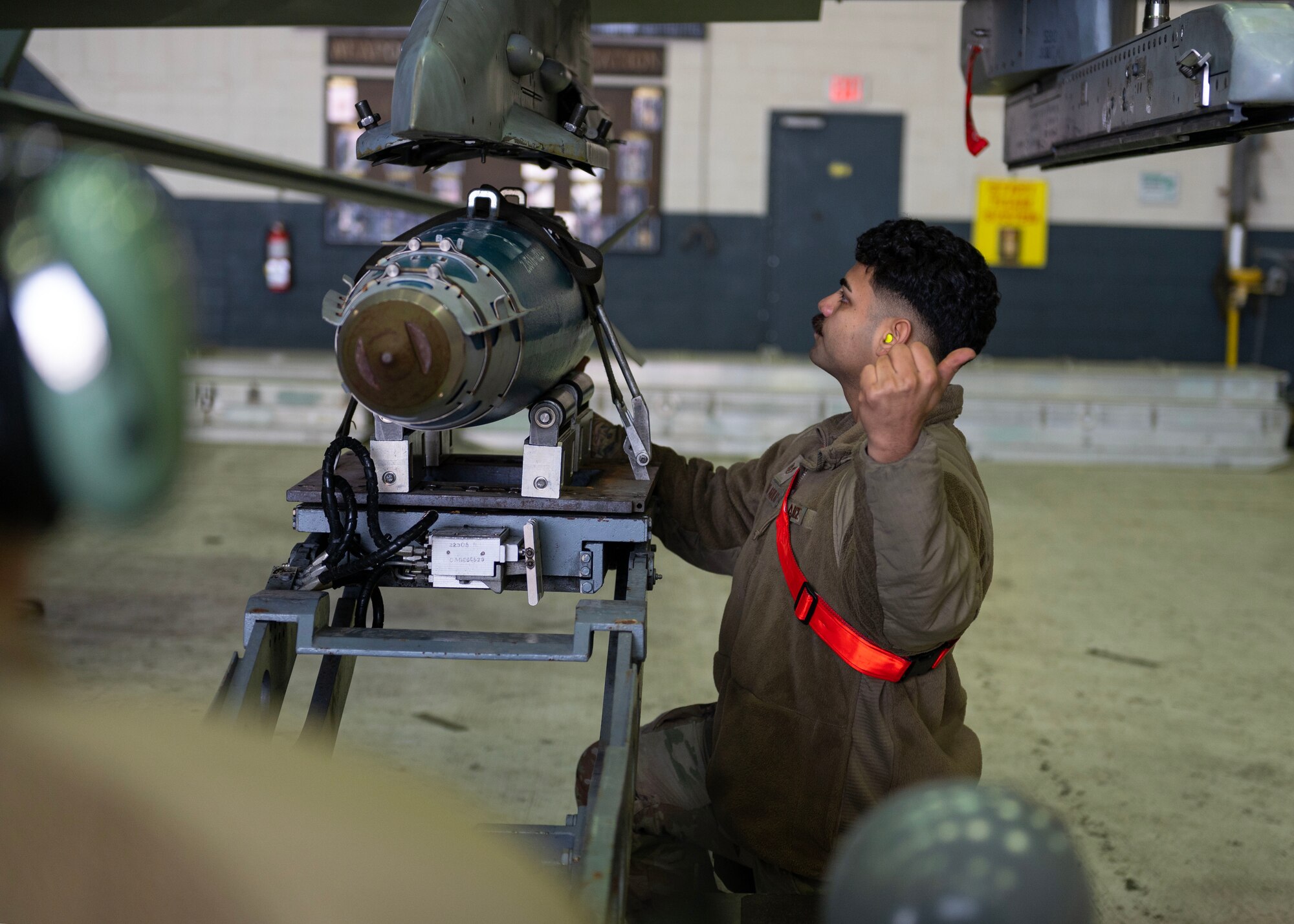 U.S. Air Force Staff Sgt. Jorge Aparicio Aguilar, 36th Fighter Generation Squadron weapons load crew chief, lines-up a GBU-38 Joint Direct Attack Munition Bomb to be placed onto a F-16 Fighting Falcon during a weapons load crew of the quarter competition at Osan Air Base, Republic of Korea, Jan. 5, 2024. Load crew competitions promote a competitive environment where Airmen display their skills and abilities while competing against other teams. (U.S. Air Force photo by Staff Sgt. Aubree Owens)
