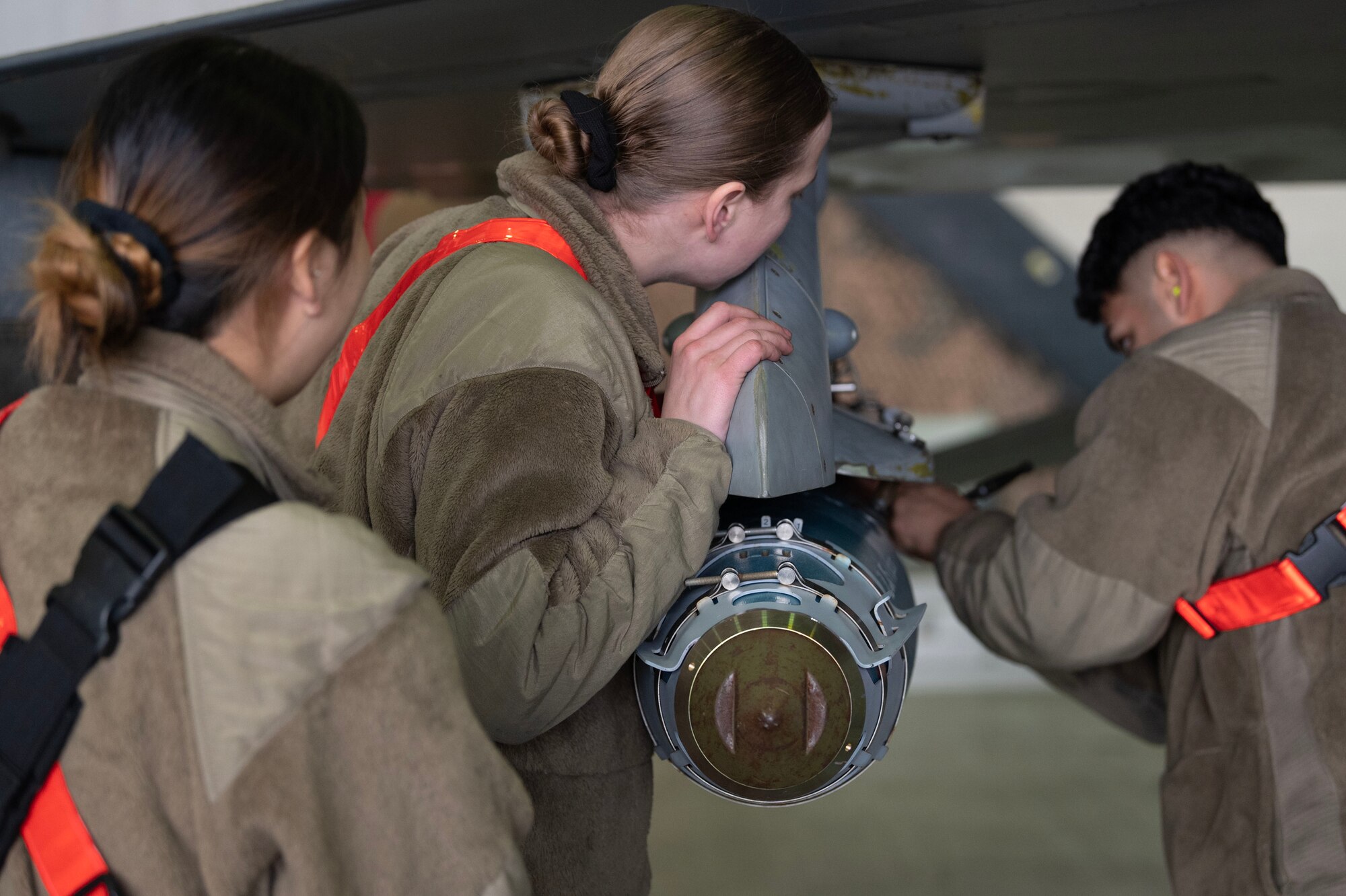 From the left, U.S. Air Force Senior Airman Hannah Noh, Senior Airman Erin Williamson, Staff Sgt. Jorge Aparicio Aguilar, 36th Fighter Generation Squadron weapons load crew members, participate during a weapons load crew of the quarter competition at Osan Air Base, Republic of Korea, Jan. 5, 2024. As part of the competition, teams are evaluated on how quickly and efficiently they can inspect and load munitions onto their respective aircraft. (U.S. Air Force photo by Staff Sgt. Aubree Owens)