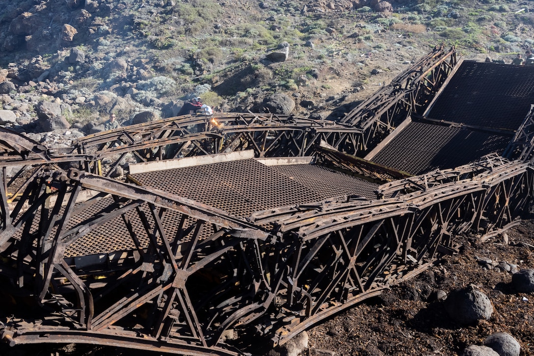 U.S. Marine Corps Lance Cpl. Rohman Papayev, a metal worker with Marine Wing Support Squadron (MWSS) 373, Marine Aircraft Group 38, 3rd Marine Aircraft Wing, cuts metal remains of the Bailey Bridge with an air carbon arc cutting system during a bridge demolition operation as part of phase I of Strategic Mobility Exercise (STRATMOBEX) II at San Clemente Island, California, Jan. 6, 2024. During phase I, MWSS-373 demolished a hazardous bridge that hindered range control’s ability to insert targets into the Shore Bombardment Area of San Clemente Island. Phase I set conditions for phases II and III of STRATMOBEX II, the construct of a shallow water crossing and follow on missions. (U.S. Marine Corps photo by Lance Cpl. Jennifer Sanchez)