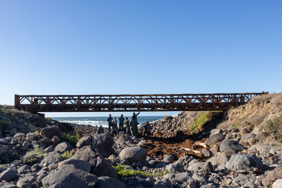 U.S. Marines with Marine Wing Support Squadron (MWSS) 373, Marine Air Control Group 38, 3rd Marine Aircraft Wing, inspect damage and deterioration on the Bailey Bridge during a bridge demolition operation as part of phase I of Strategic Mobility Exercise (STRATMOBEX) II at San Clemente Island, California, Jan. 4, 2024. During phase I, MWSS-373 demolished a hazardous bridge that hindered range control’s ability to insert targets into the Shore Bombardment Area of San Clemente Island. Phase I set conditions for phases II and III of STRATMOBEX II, the construct of a shallow water crossing and follow on missions. (U.S. Marine Corps photo by Sgt. Luc Boatman)
