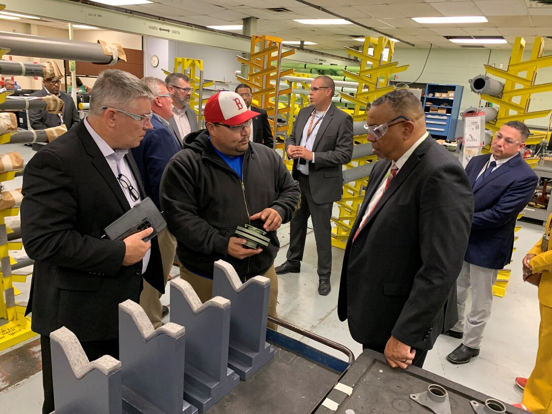 Group of men in factory looking at parts.