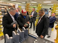 Group of men in factory looking at parts.