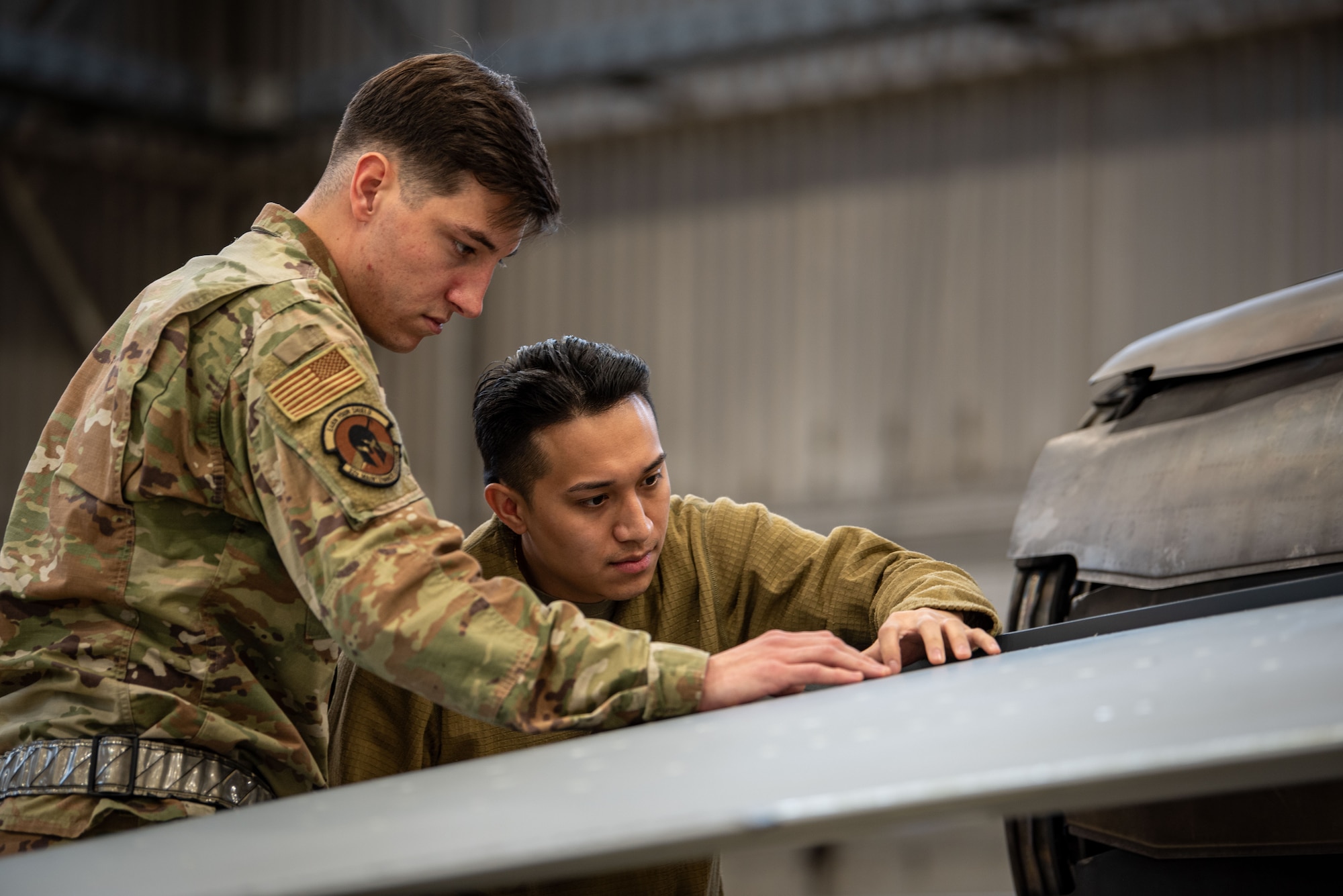 U.S. Air Force Staff Sgt. Mapote Blazelee and Staff Sgt. Meskos Evangelos, 52nd Maintenance Squadron aircraft structural maintenance journeymen, perform a periodic maintenance inspection on an F-16 Fighting Falcon fighter jet at Spangdahlem Air Base, Germany, Nov. 30, 2023.
