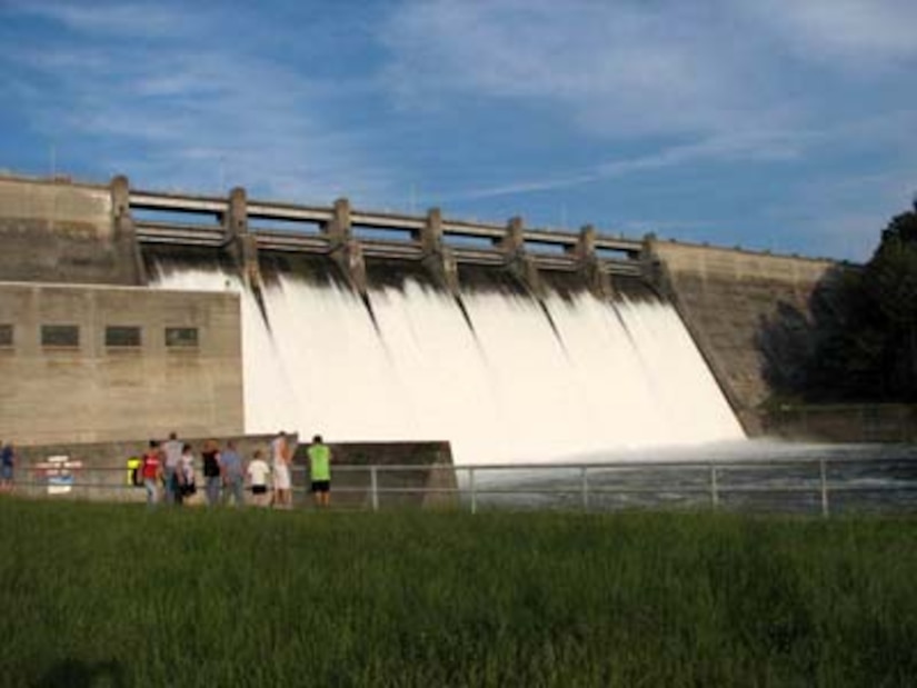 Photo of Dale Hollow Dam, with a dam with water pouring through the turbines, people in lower left looking up at it.