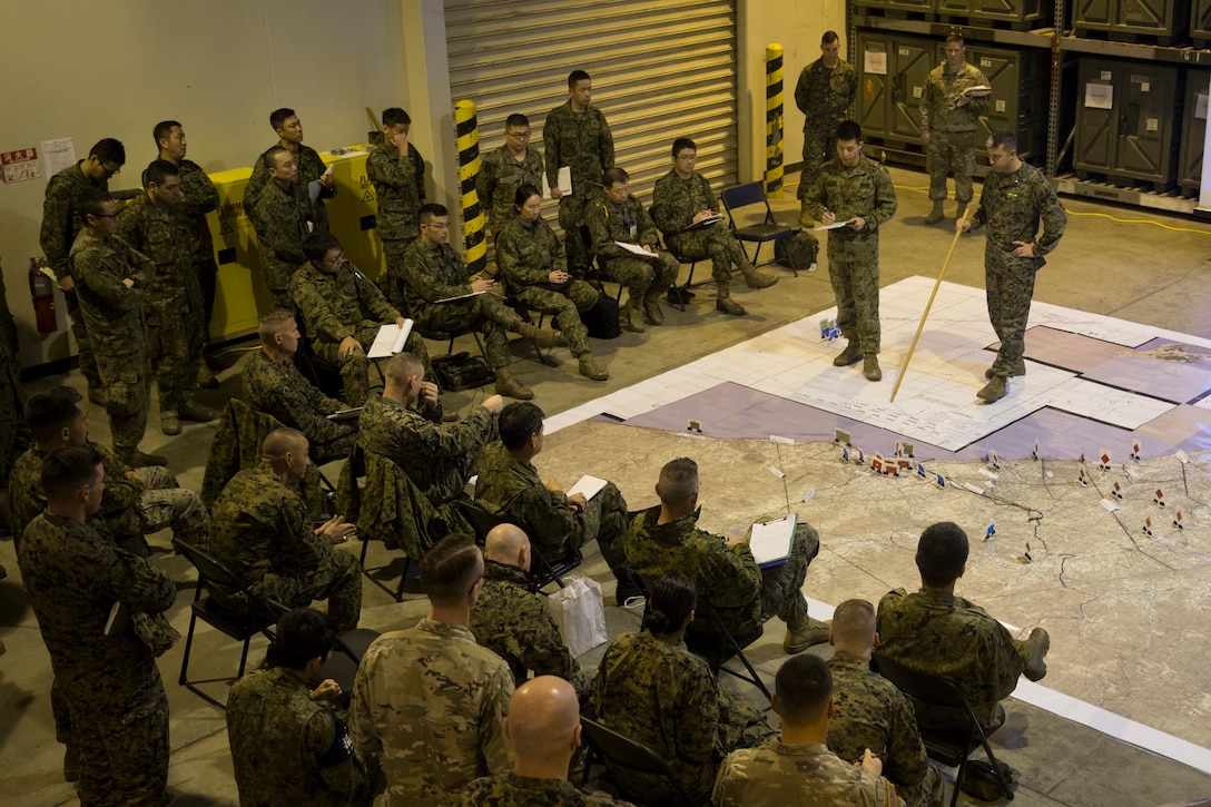 U.S. Marine Corps Lt. Col. Joseph McAlarnen, right, with 3D Marine Expeditionary Brigade, and Capt. Atsushi Kawabata, left, with the Japan Ground Self-Defense Force Amphibious Rapid Deployment Brigade, brief during a Rehearsal of Concept drill, which simulates various courses of action with U.S. forces and Japanese member during Exercise Yama Sakura 77 on Camp Courtney, Okinawa, Japan, Dec. 7, 2019. Participants included Marines from 3D MEB, Soldiers from U.S. Army I Corps and 40th Infantry Division, and members from the JGSDF Eastern Army, Western Army, and ARDB.