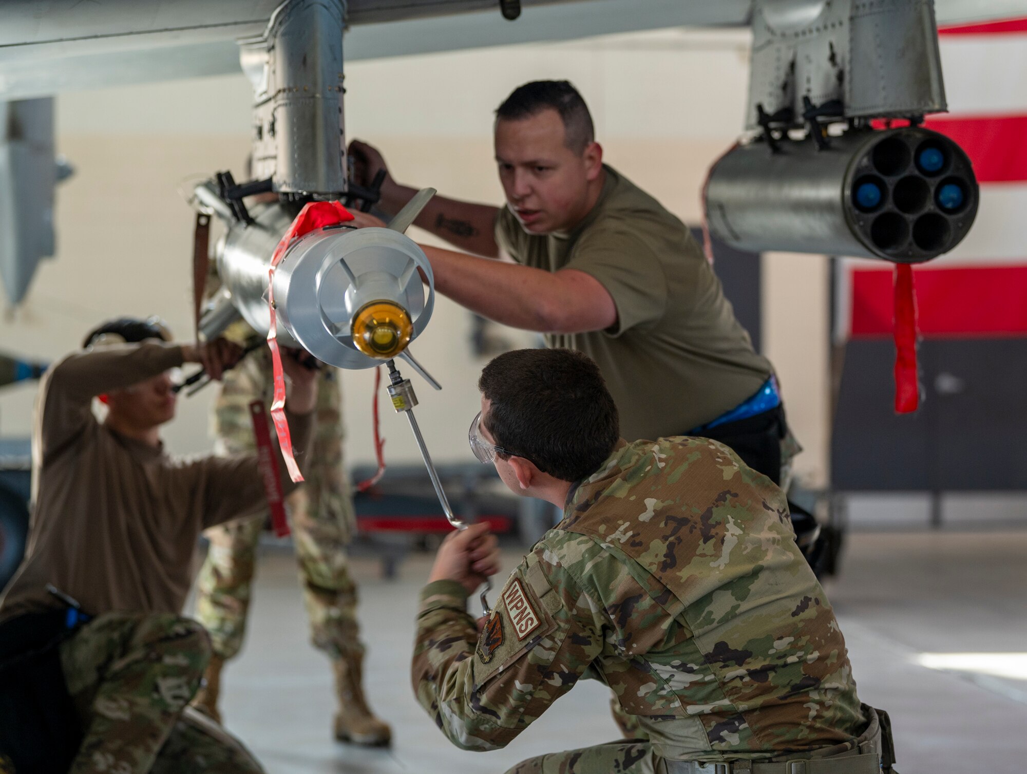 U.S. Air Force Staff Sgt. Concepcion Rodelo (top), Airman 1st Class Aaron Bowie (bottom) and Senior Airman Dylan Gleason-Pritts (back), 74th Fighter Generation Squadron load crew members, load weapons on an A-10C Thunderbolt II at Moody Air Force Base, Georgia, Jan. 5, 2024. Two three-man weapons teams compete against each other several times a year in quarterly competitions. (U.S. Air Force photo by Airman 1st Class Leonid Soubbotine)