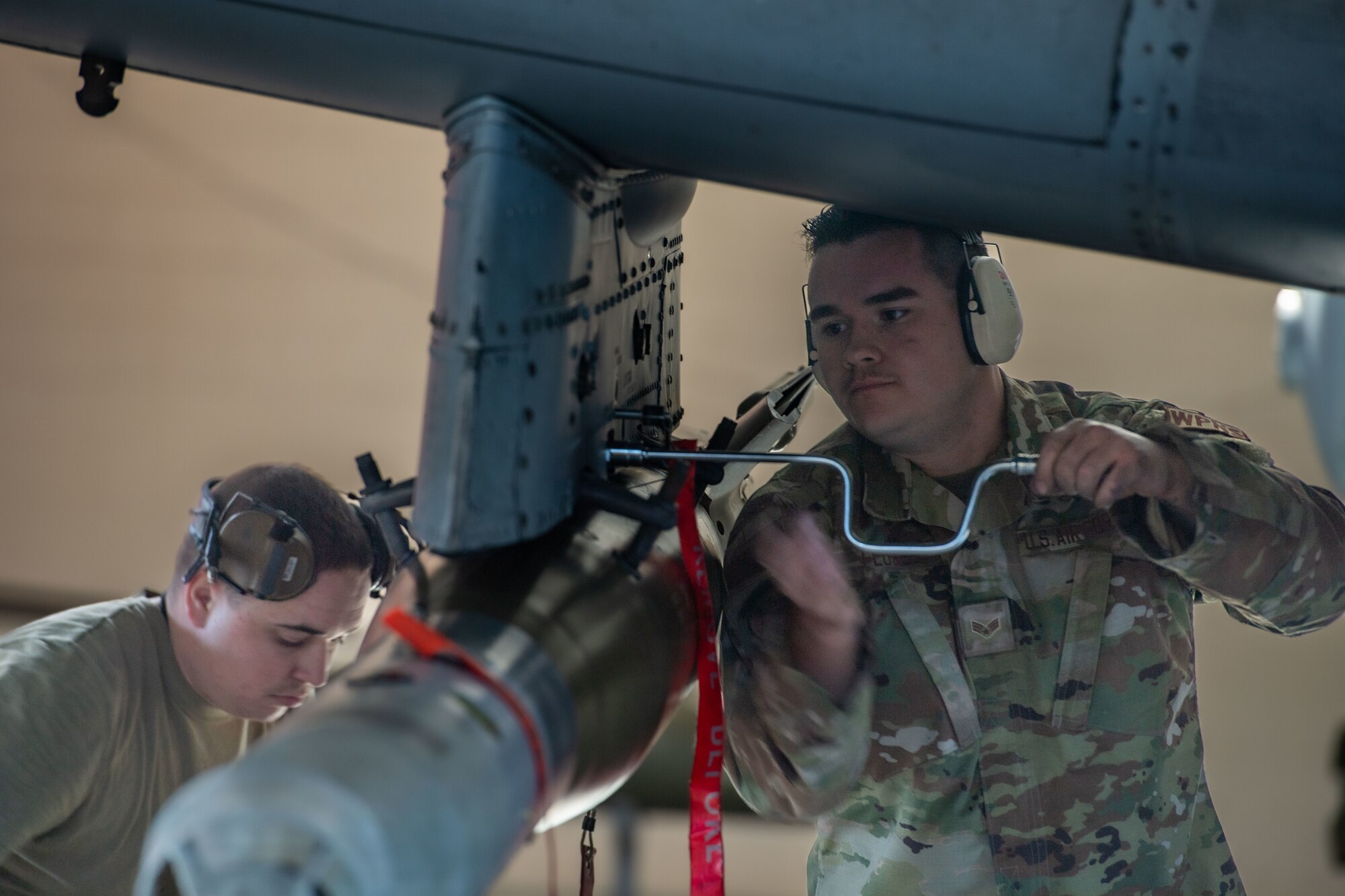 U.S. Air Force Senior Airman Mathew Flores, 75th Fighter Generation Squadron load crew member, tightens a bolt on an A-10C Thunderbolt II at Moody Air Force Base, Georgia, Jan 5, 2024. Flores helped his team load munitions onto the aircraft as quickly and efficiently as possible in hopes of winning a quarterly weapons load competition. (U.S. Air Force photo by Airman Cade Ellis)