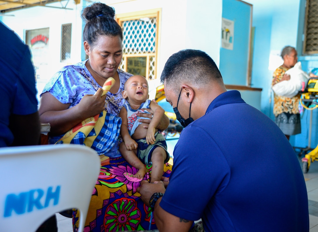 A Navy doctor consults a woman and her child.