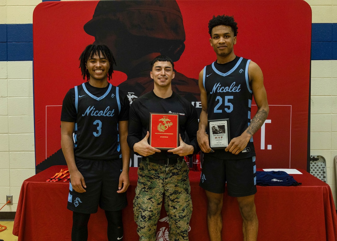 U.S. Marine Corps Staff Sgt. David Ramirez, center, production recruiter with Recruiting Sub-Station Milwaukee, Recruiting Station Milwaukee, 9th Marine Corps District, presents David Bolden, right, and Davion Hannah, left, Nicolet High School students with the Marine Corps Player of the Game award at the 2023 Rick Majerus WBY Shootout, Concordia University, Concordia, Wisconsin, Dec. 28, 2023. Recruiting Station Milwaukee partners with Mike McGivern and the Big920 AM to present the Marine Corps Player of the Game award to student athletes who embody the spirit of teamwork, perseverance and discipline. (U.S. Marine Corps photo by Cpl. Collette Hagen)