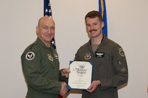 Chief of Staff of the Air Force Gen. David Allvin, left, presents the 2022 Mackay Trophy certificate to Maj. Stephen Keck, a U.S. Air Force F-15E pilot, during a ceremony at Nellis Air Force Base, Nev., Jan. 11, 2024. Keck received this honor for his actions while serving as the Defensive Counter-Air Team Lead for the 335th Expeditionary Fighter Squadron during a deployed mission. (U.S. Air Force photo by Airman 1st Class Jordan McCoy)