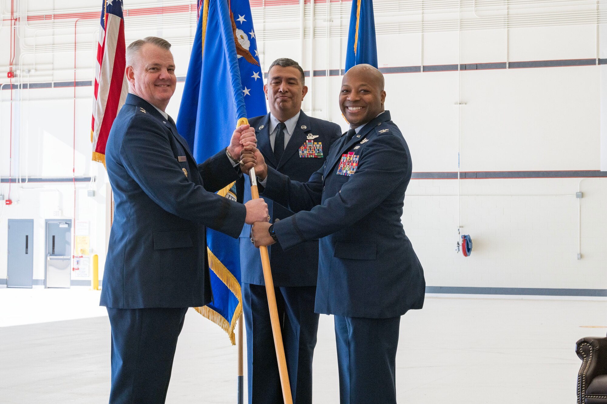 Maj. Gen. D. Scott Durham, 4th Air Force commander, passes the guidon to Col. Patrick L. Brady-Lee (right) as he assumes command of the 349th Air Mobility Wing on January 7, 2024, at Travis Air Force Base, California. (US Air Force photo by Tech. Sgt. Ryan Green)