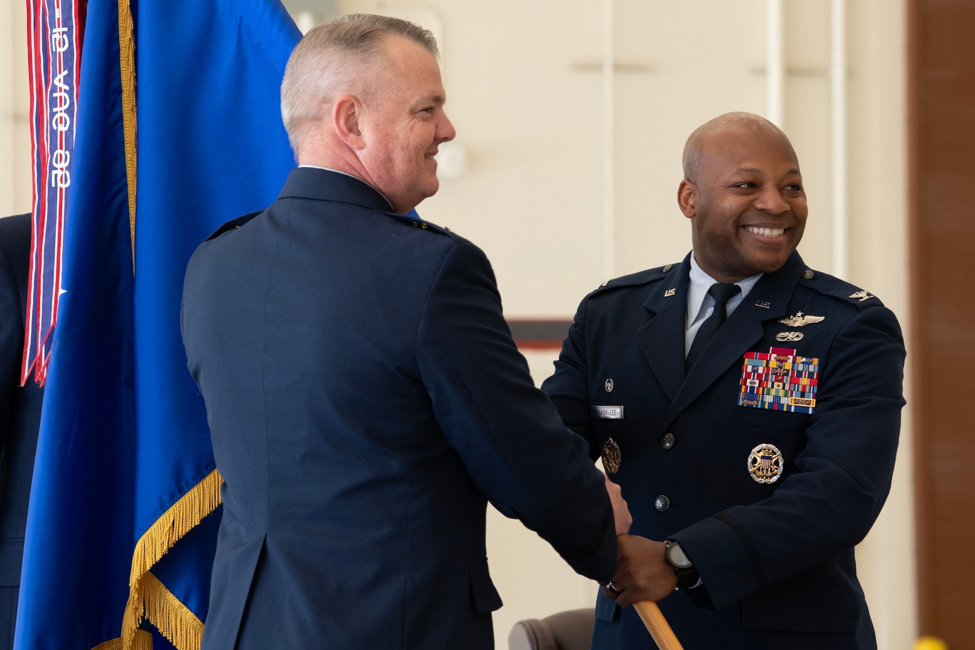 Maj. Gen. D. Scott Durham, 4th Air Force commander, passes the guidon to Col. Patrick L. Brady-Lee (right) as he assumes command of the 349th Air Mobility Wing on January 7, 2024, at Travis Air Force Base, California. (US Air Force photo by Tech. Sgt. Ryan Green)