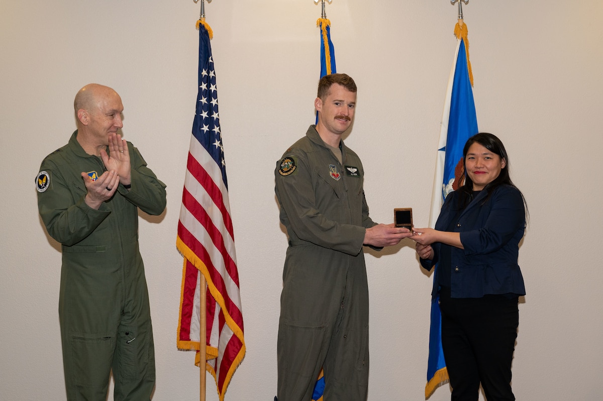 Chief of Staff of the Air Force Gen. David Allvin applauds U.S. Air Force Maj. Stephen Keck, center, an F-15E pilot assigned to the 53rd Wing, as he receives the 2022 Mackay Trophy coin from Tina Wu, director of Membership and Awards of the National Aeronautic Association, during a ceremony at Nellis Air Force Base, Nev., Jan. 11, 2024. Awarded for the most meritorious flight of the year by an Air Force individual, group, or organization, the Mackay Trophy is one of the longest-standing aviation awards in the nation. (U.S. Air Force photo by Airman 1st Class Jordan McCoy)