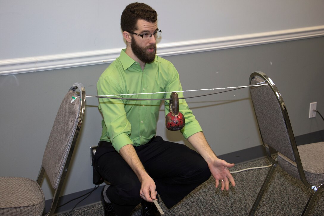 An engineer sits between two chairs with a string tied in between them.