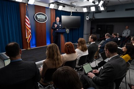 A man in a military uniform stands behind a lectern. Behind him is a sign that says "The Pentagon."