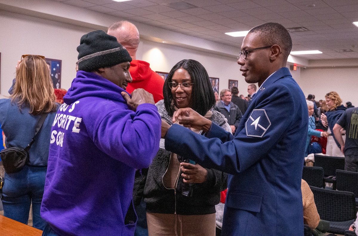 A newly graduated U.S. Space Force Guardian presents the U.S. Space Force Family lapel pin to a family member during a Basic Military Training graduation ceremony at Joint Base San Antonio-Lackland, Texas, Dec. 27, 2023. In a move that celebrates both the service members and their families, graduating Guardians will now present the Delta-shaped U.S. Space Force Family lapel pins to their loved ones during graduation week. (U.S. Air Force photo by 2d Lt. Kate E. Anderson)