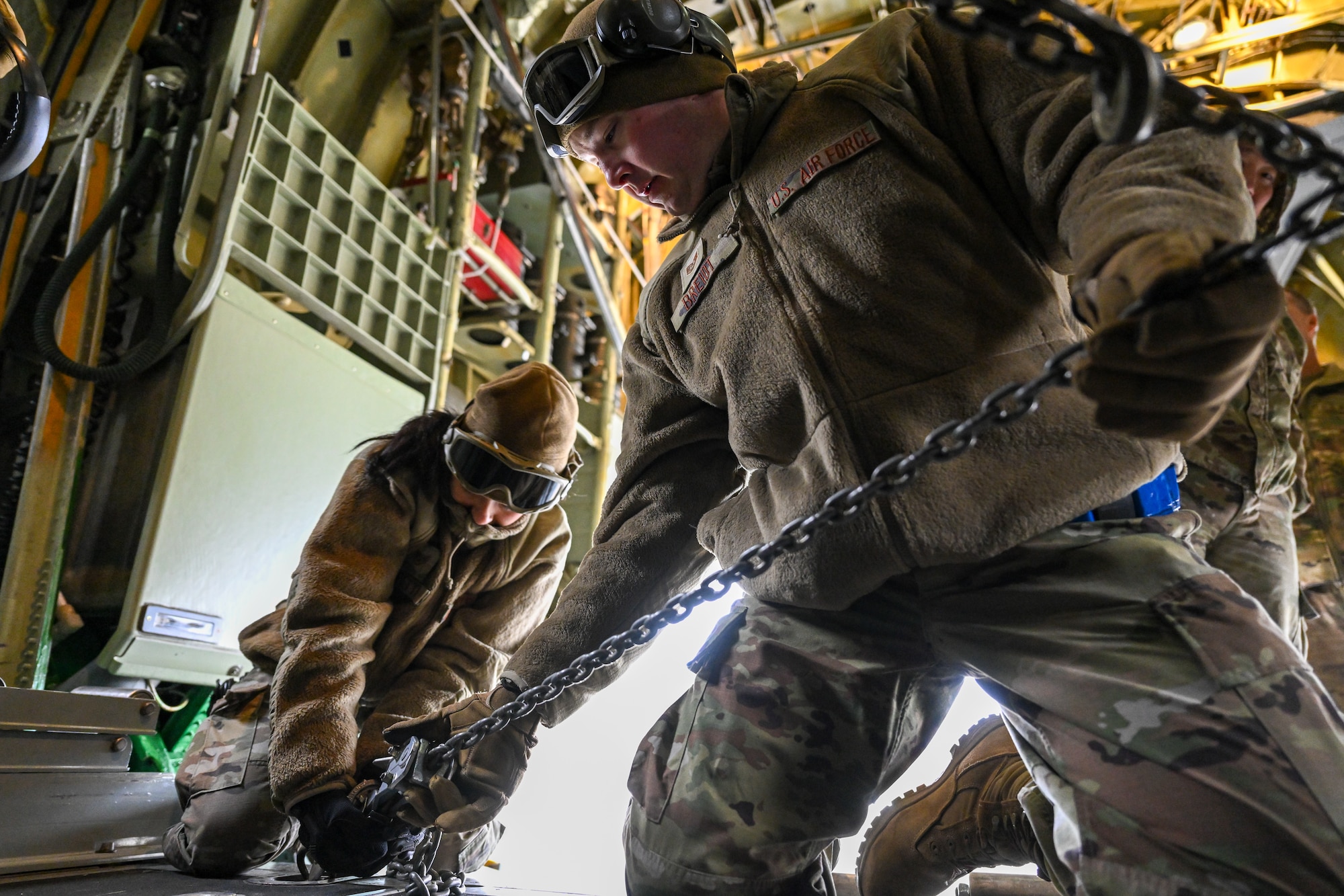 Staff Sgt. Miranda Petti and Tech. Sgt. Peter Breidt, port dawgs with the 46th Aerial Port Squadron, Dover Air Force Base, Delaware, chain a Humvee down in the cargo bay of a C-130H Hercules aircraft stationed at Youngstown Air Reserve Station, Ohio on Jan. 6, 2024.