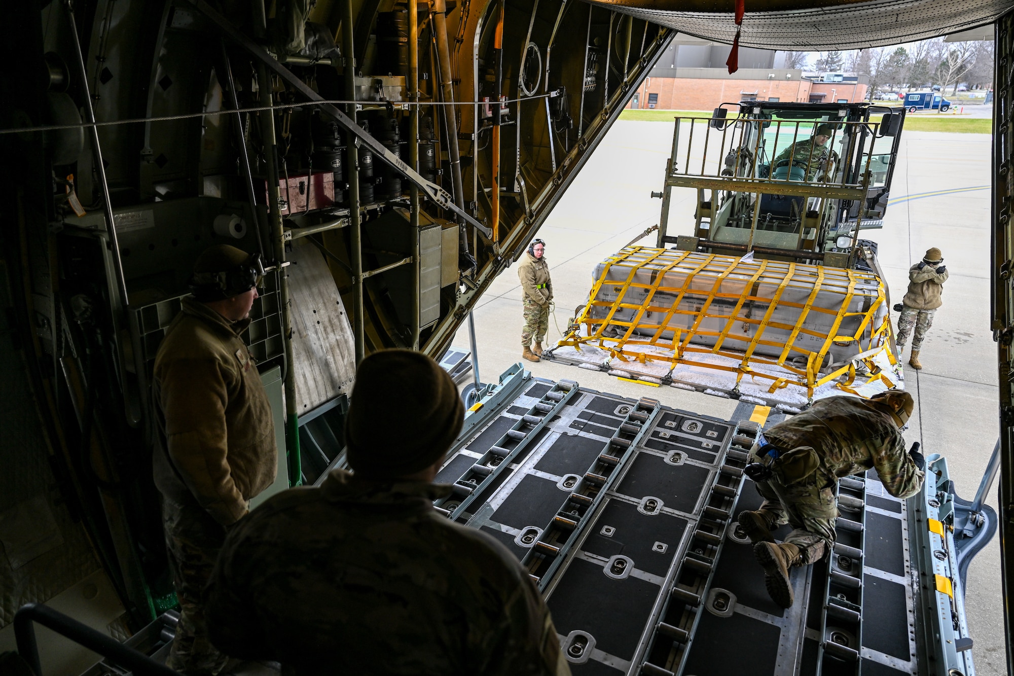 A pack of aerial porters with the 46th Aerial Port Squadron, Dover Air Force Base, Delaware, load a pallet into the cargo bay of a C-130H Hercules aircraft stationed at Youngstown Air Reserve Station, Ohio, on Jan. 6, 2024.