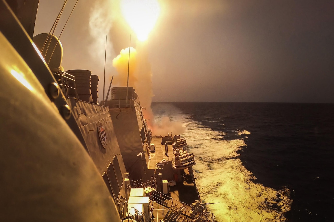 A missile launches from a ship at sea.