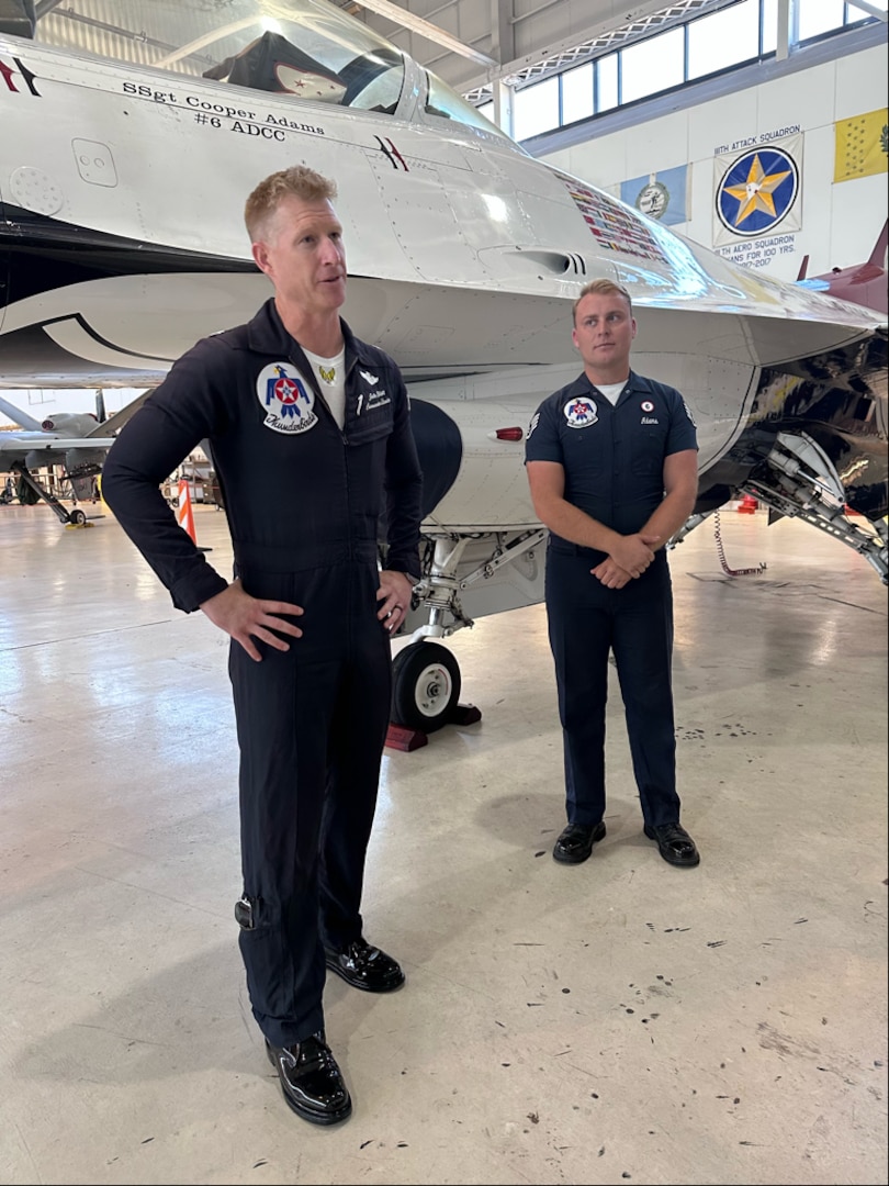two men stand in front of a jet