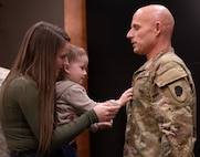 Braxton Defenbaugh, grandson of newly promoted Chief Warrant Officer 5 Brandon Defenbaugh, places new rank on his uniform during a promotion ceremony Jan. 11 at Camp Lincoln, Springfield, Illinois.