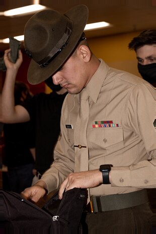 U.S. Marine Corps Sgt. Ricardo Camacho, a drill instructor with Receiving Company, Support Training Battalion, looks through a recruit's belongings with Hotel Company, 2nd Recruit Training Battalion, during receiving at Marine Corps Recruit Depot San Diego, Jan. 8, 2024. During the receiving process recruits are checked for contraband, given haircuts, make phone calls home, and are issued gear. Camacho is a native of Chicago, Illinois. (U.S. Marine Corps photo by Lance Cpl. Janell B. Alvarez)