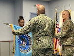 Navy Capt. Nicola Gathright, DCMA East Region commander, and Navy Capt. Le-Hesh Graham, DCMA Northeast commander, unfurl the flag of the newly established DCMA Northeast contract management office during a ceremony Jan. 11 at East Hartford, Conn.