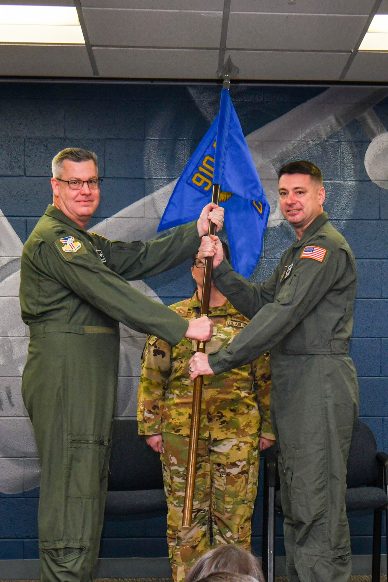 Col. Michael Maloney, commander of the 910th Airlift Wing, and Col. John Sebesta, incoming commander of the 910th Operations Group, listen to the historical significance of the guidon during Sebesta’s assumption of command ceremony on Jan. 6, 2024, at Youngstown Air Reserve Station, Ohio.