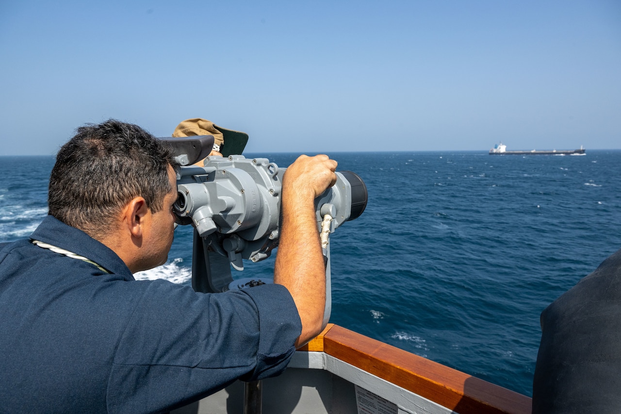 A person stands watch aboard a ship at sea.