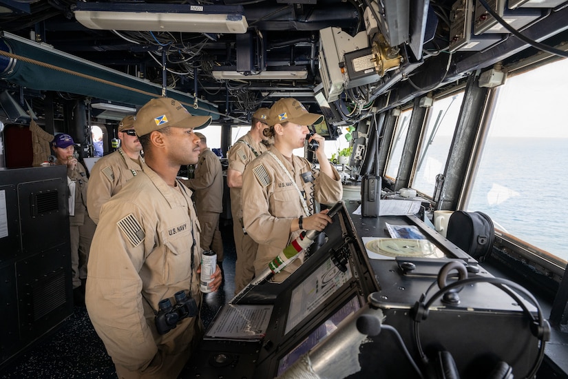 Sailors stand watch aboard a ship at sea.